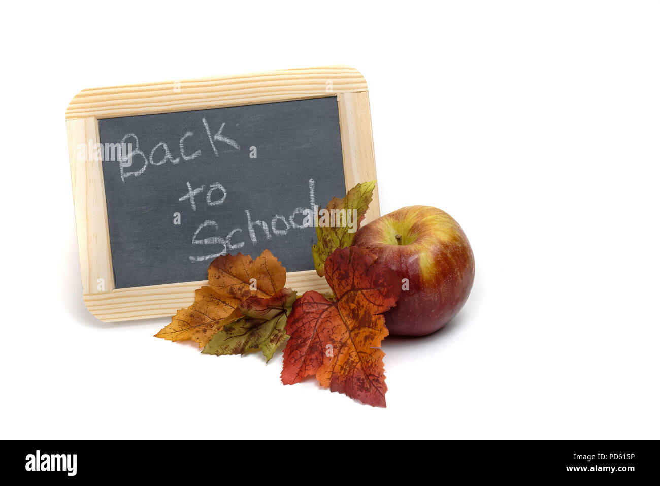 Si torna a scuola scritto su una piccola lavagna con un apple e colorato Foglie di autunno isolato su uno sfondo bianco Foto Stock