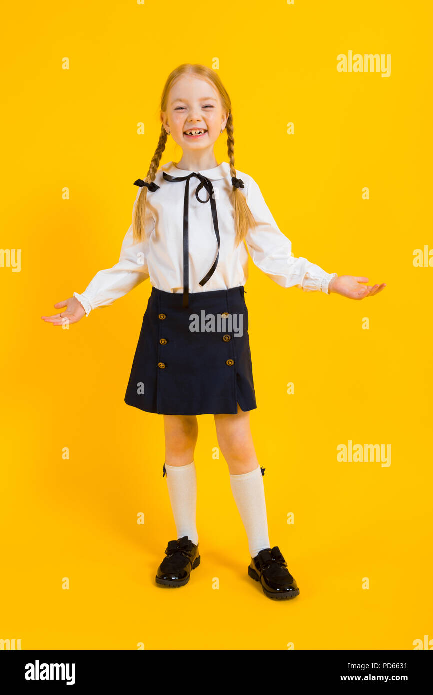 Ragazza con pigtail di colore rosso su sfondo giallo. La bella ragazza mettere le mani ai lati e risate. Foto Stock