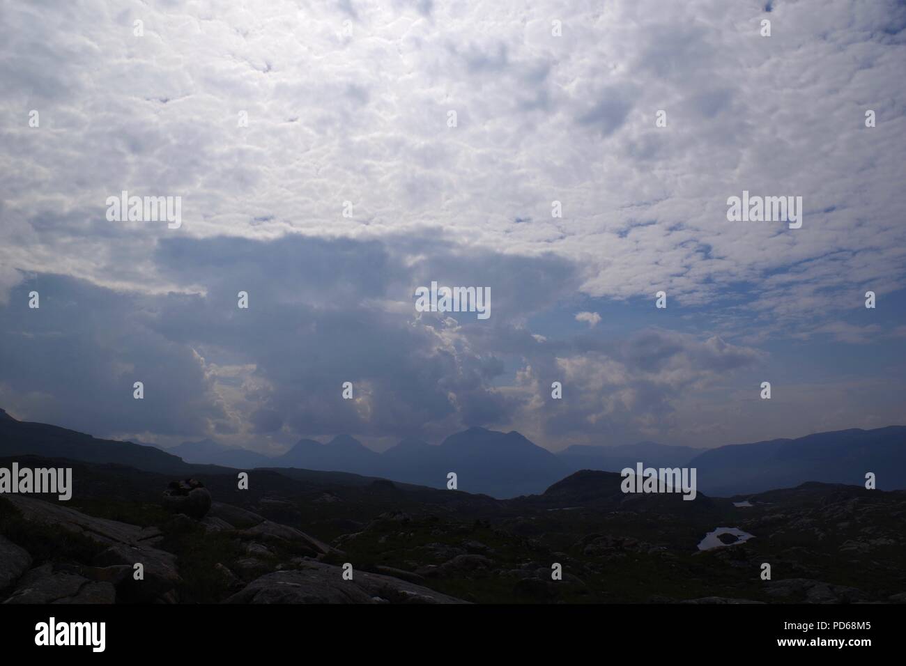 Picchi di montagna attraverso l'estate Haze sotto un cielo di nuvole Altocumulus. Torridon, Scotland, Regno Unito. Foto Stock