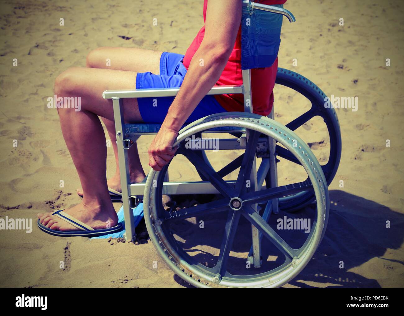 Giovane uomo su una sedia a rotelle speciale sulla spiaggia del mare con effetto vintage Foto Stock