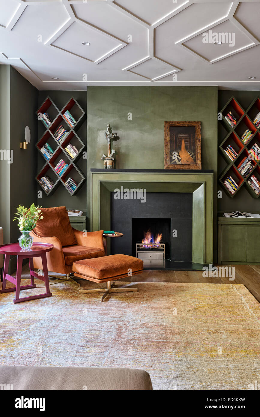 Vintage poltrona e poggiapiedi withlit fire e montato a parete a scaffali Foto Stock