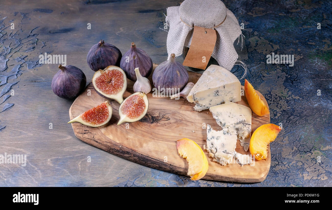 Fichi maturi, nobile formaggio con stampo, pesche su un tagliere. Foto Stock