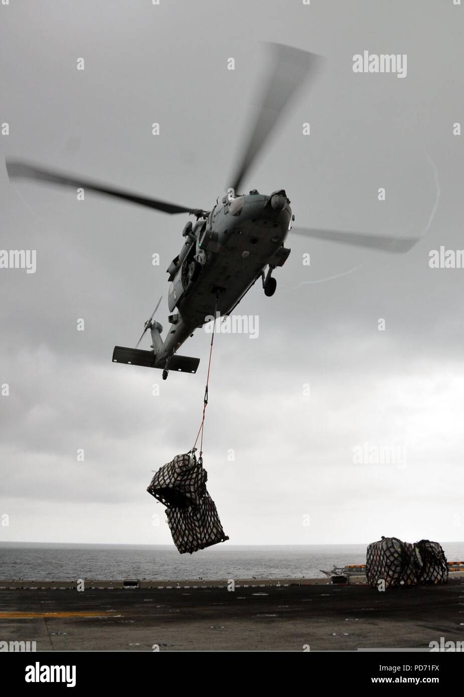 Un MH-60 elicottero Seahawk offre forniture sul ponte di volo dell'assalto anfibio nave USS Boxer (LHD 4) durante un modo sotto il rifornimento nell'Oceano Pacifico il 17 marzo 2011 Foto Stock