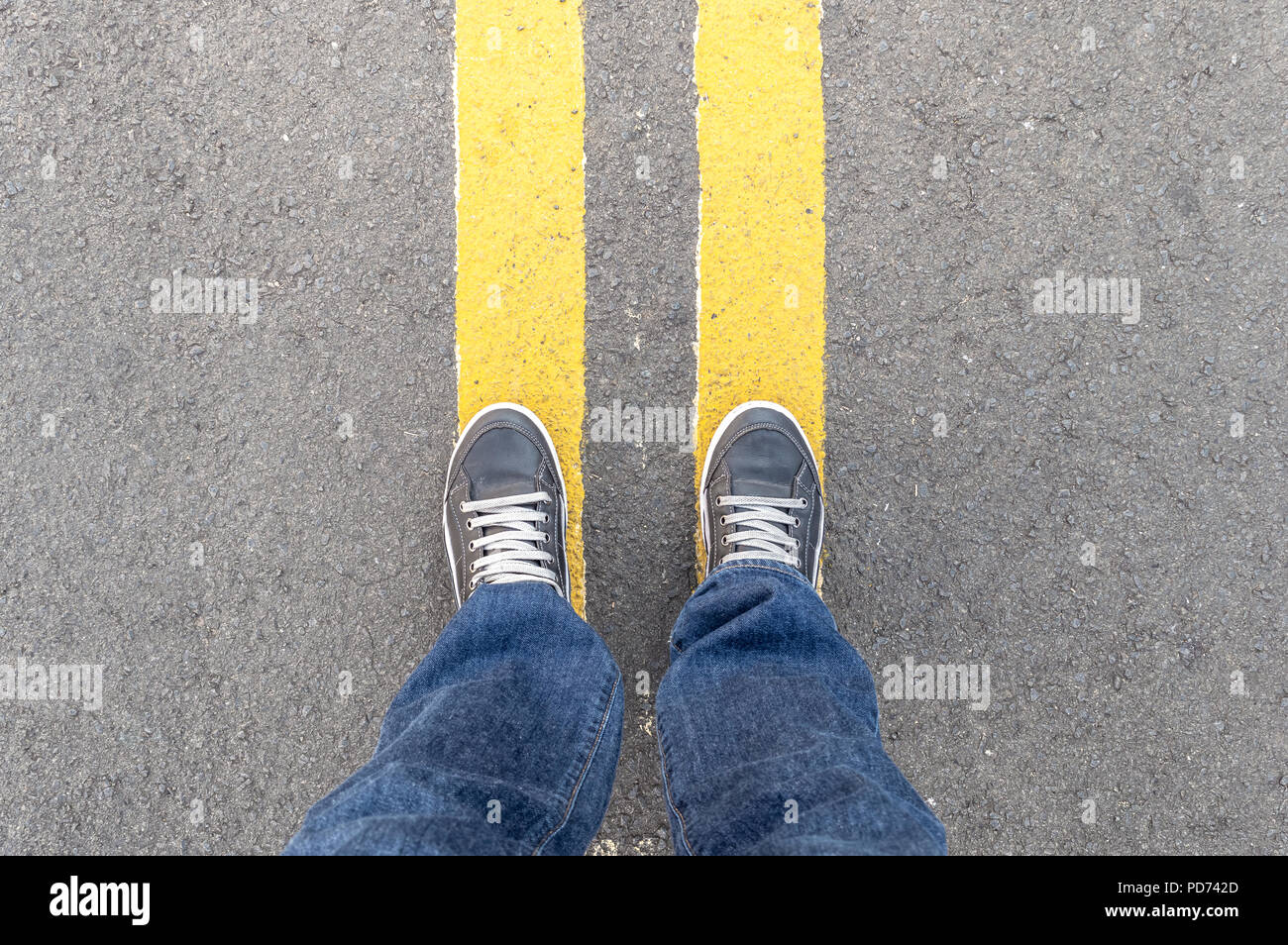 Punto di vista personale della persona per le gambe e strade delle linee di colore giallo Foto Stock