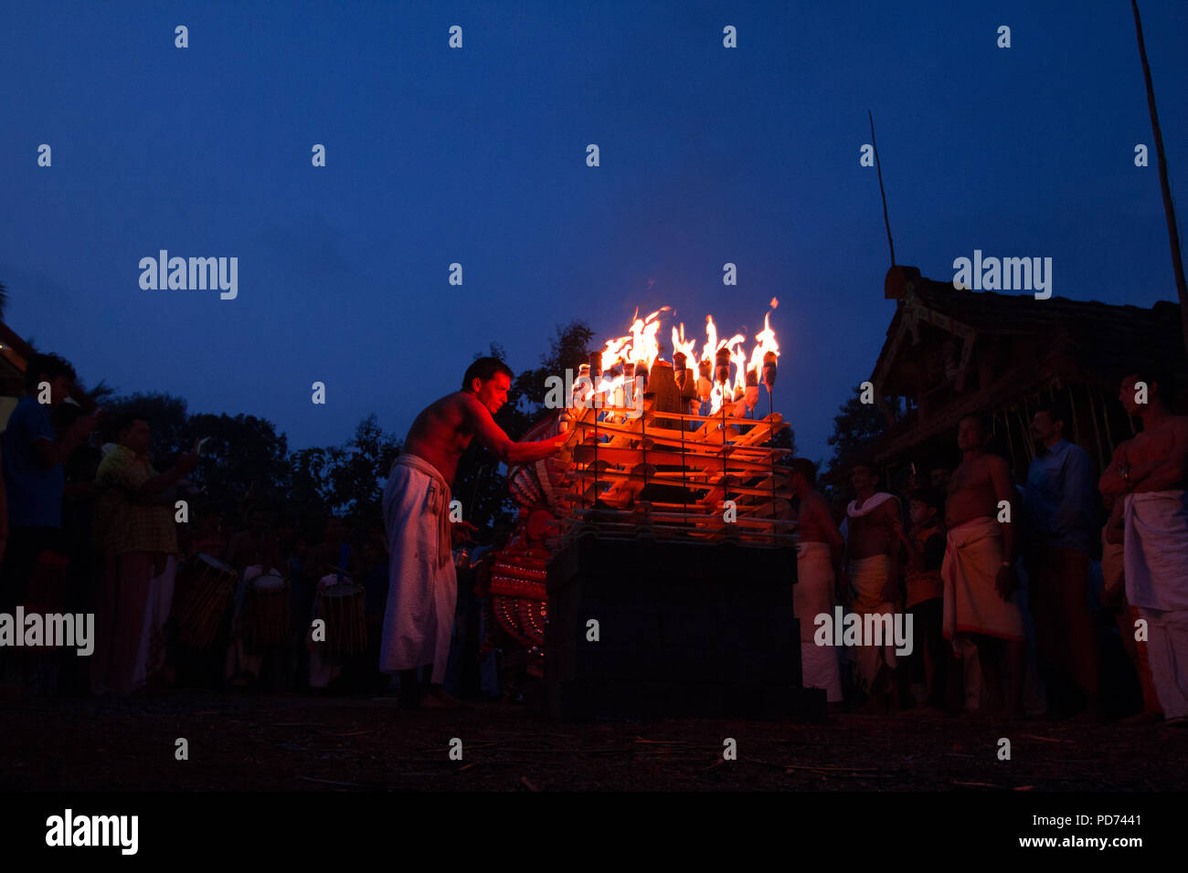 La mattina presto il rituale relativi a Theyyam. Devoto accensione della lampada al tempio tradizionale. Vishakandan Theyyam, Kaavu, Kerala. Foto Stock