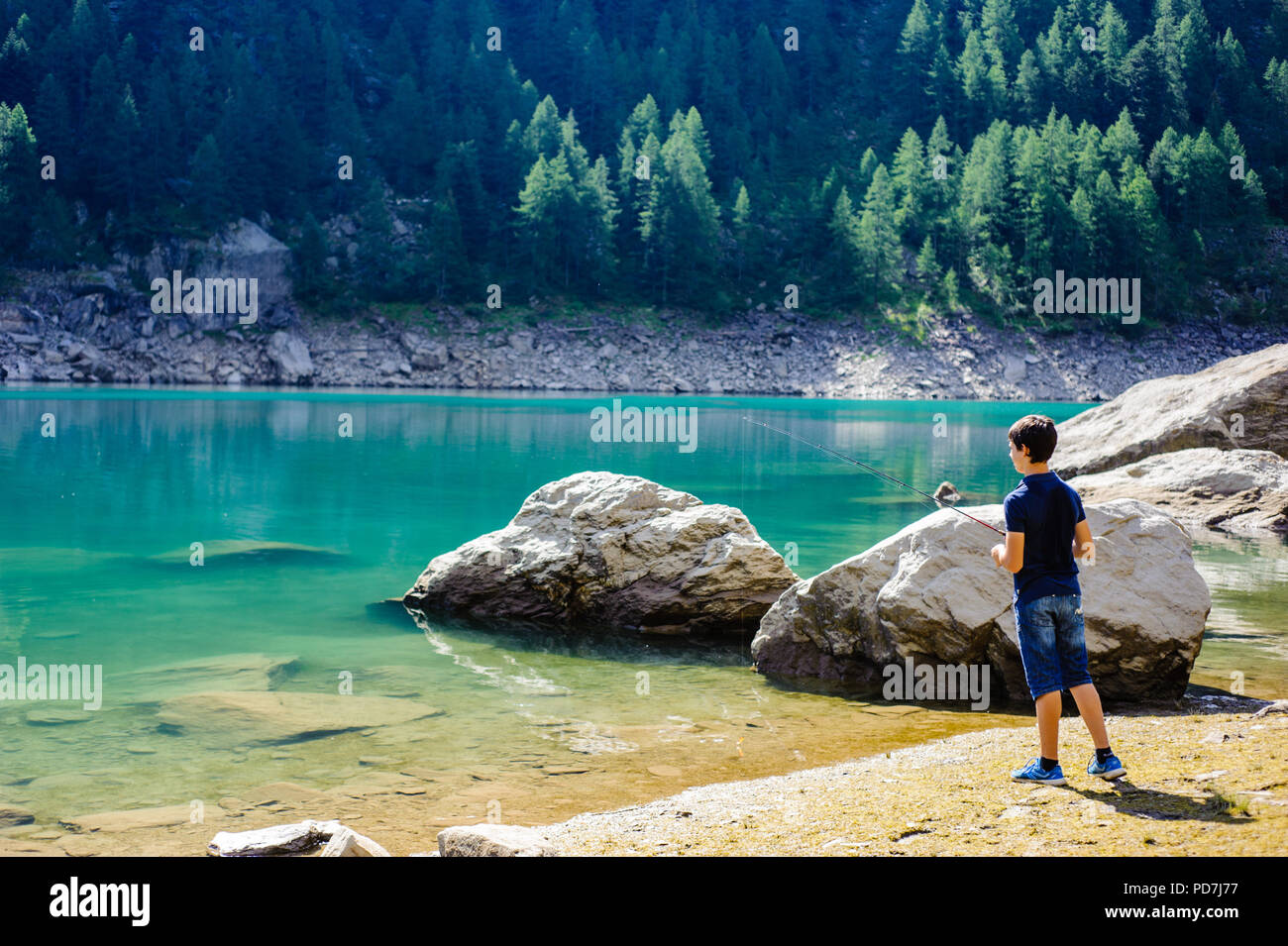 Ragazzo di pesca in alta montagna nel lago alpino, in un giorno di estate, Italia Piemonte Valle Ossola Foto Stock