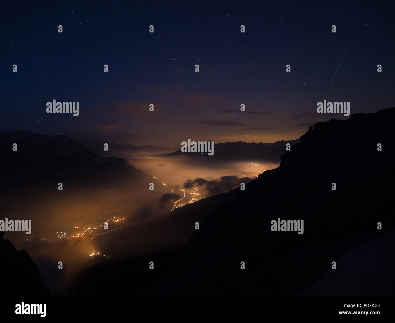 Cielo stellato e di alta gamma della montagna, italiano sulle Alpi francesi, la nebbia e la nebbia in vally con villaggi incandescente qui di seguito. Foto Stock