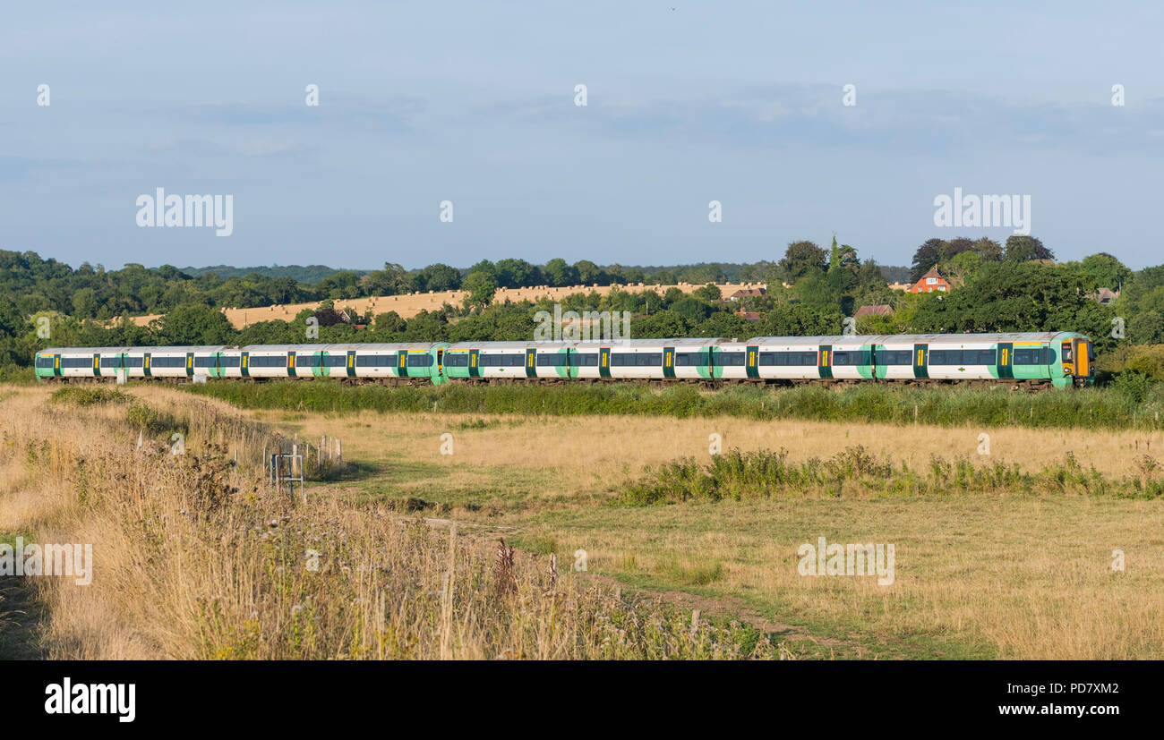 Rampa meridionale classe 377 Electrostar treno in viaggio attraverso la campagna nella luce della sera d'Estate nella valle di Arun nel West Sussex, in Inghilterra, Regno Unito Foto Stock