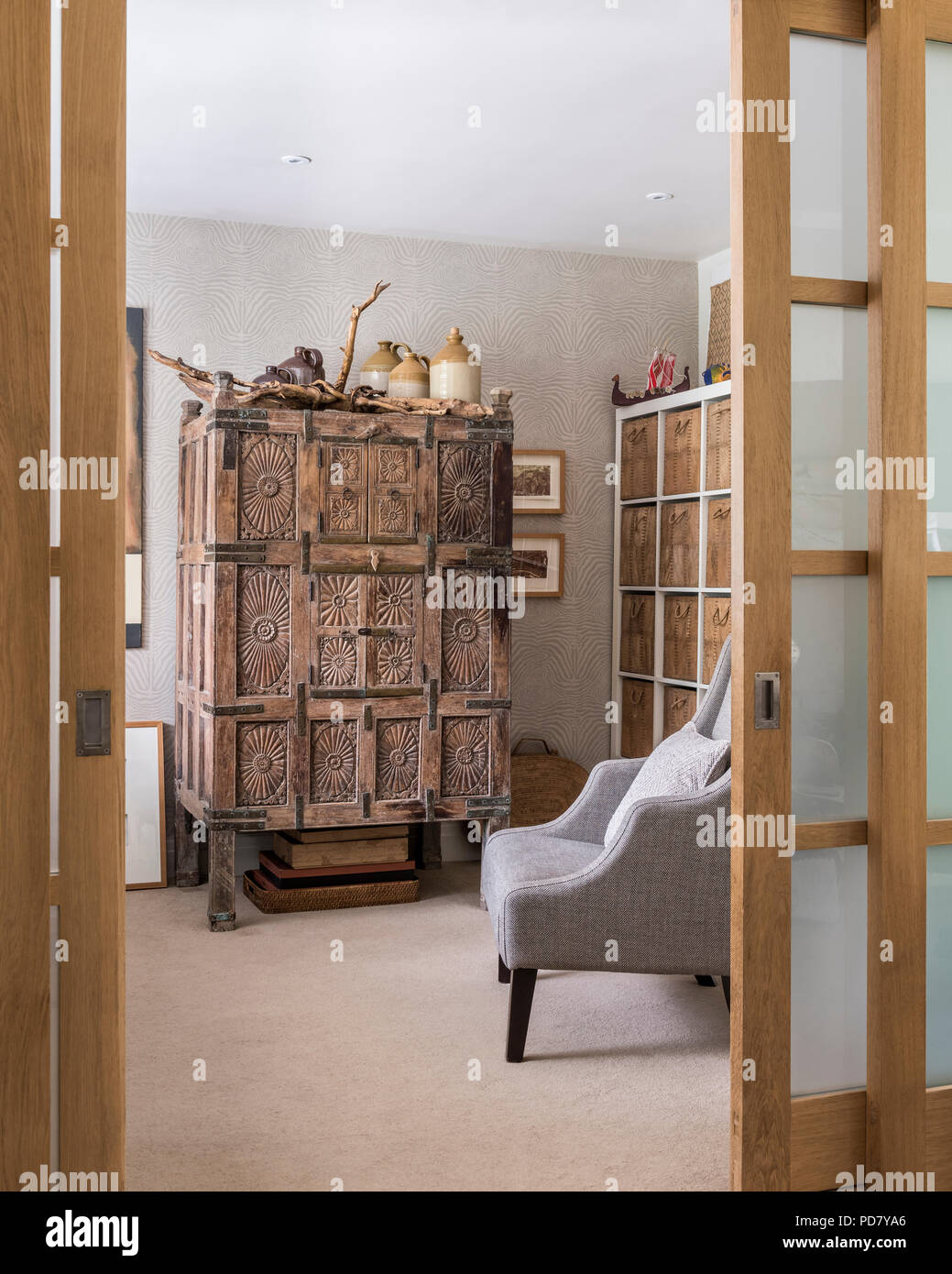 Vista attraverso le porte slidiing in home office con un sacco di Scaffali da parete e una vecchia cassa di legno da Oman in ingresso della lobby. Foto Stock