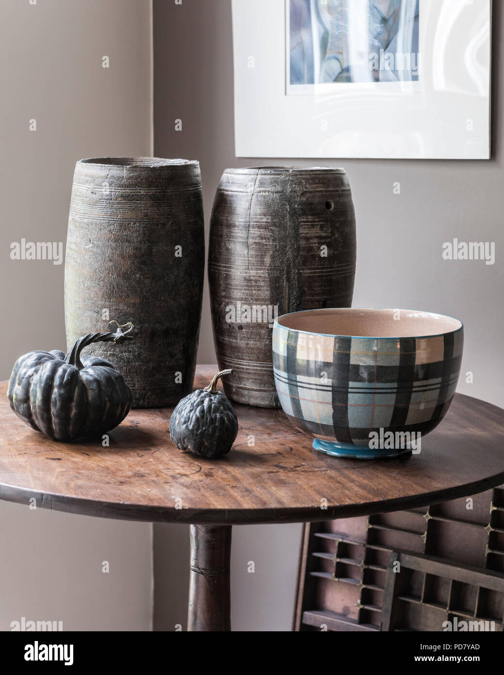 Due vasi di legno dal Sud Africa sono visualizzati su un piccolo tavolo in salotto con zucche essiccate e una ciotola da anta. Foto Stock
