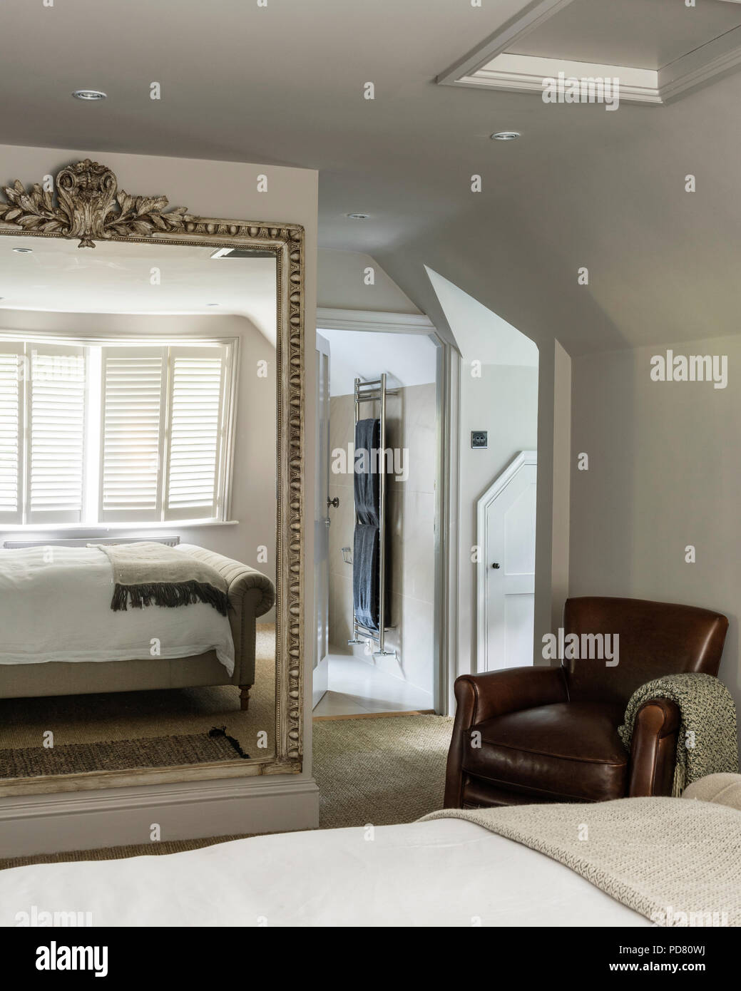 Poltrona in pelle e di un grande specchio nella camera da letto con Pentlow abbottonata letto doppio da divani & Stuff Foto Stock