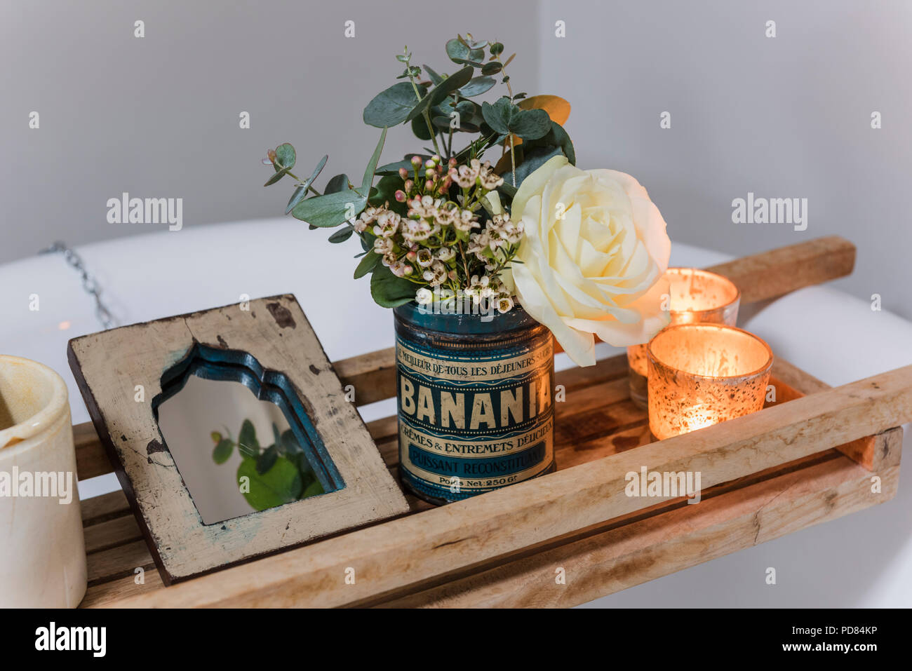 Posey freschi di fiori in stagno vintage e tealight sul bagno di legno rack Foto Stock