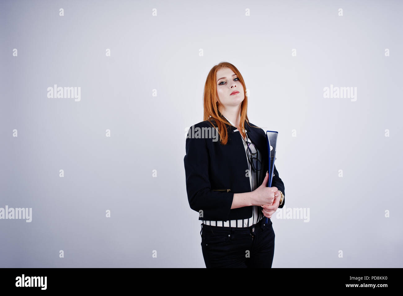 Ritratto di una imprenditrice redheaded indossando camicia a righe e una giacca con una cartella di blu. Foto Stock