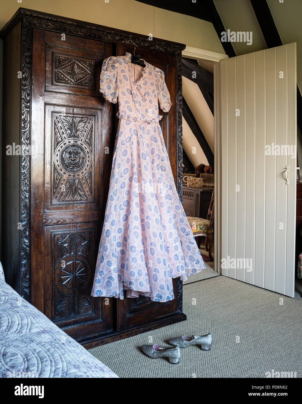 1930s Vintage dress appeso su antichi in legno di quercia intagliato armadio Foto Stock