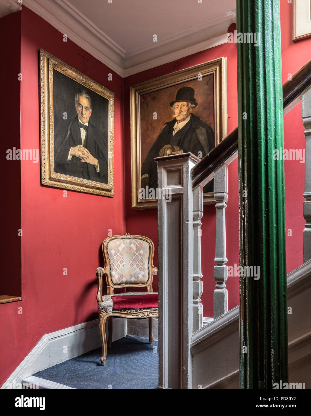 Ritratti incorniciata sulla scala rossa parete del disegno di Londra Club Foto Stock