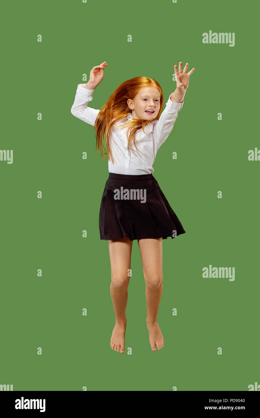 Giovani caucasici felice teen ragazza di saltare in aria, isolato sul verde di sfondo per studio. Bellissima femmina di metà lunghezza verticale. Le emozioni umane, espressione facciale concetto. Foto Stock
