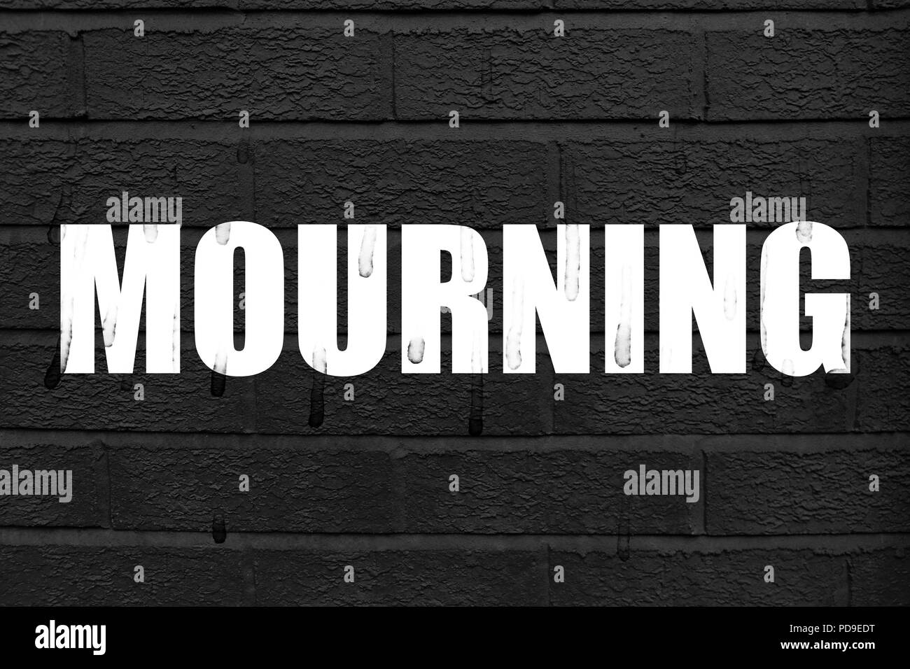 La parola 'MOURNING' sul muro nero lo sfondo con sentieri di lacrime sulle lettere in bianco e lo sfondo Foto Stock