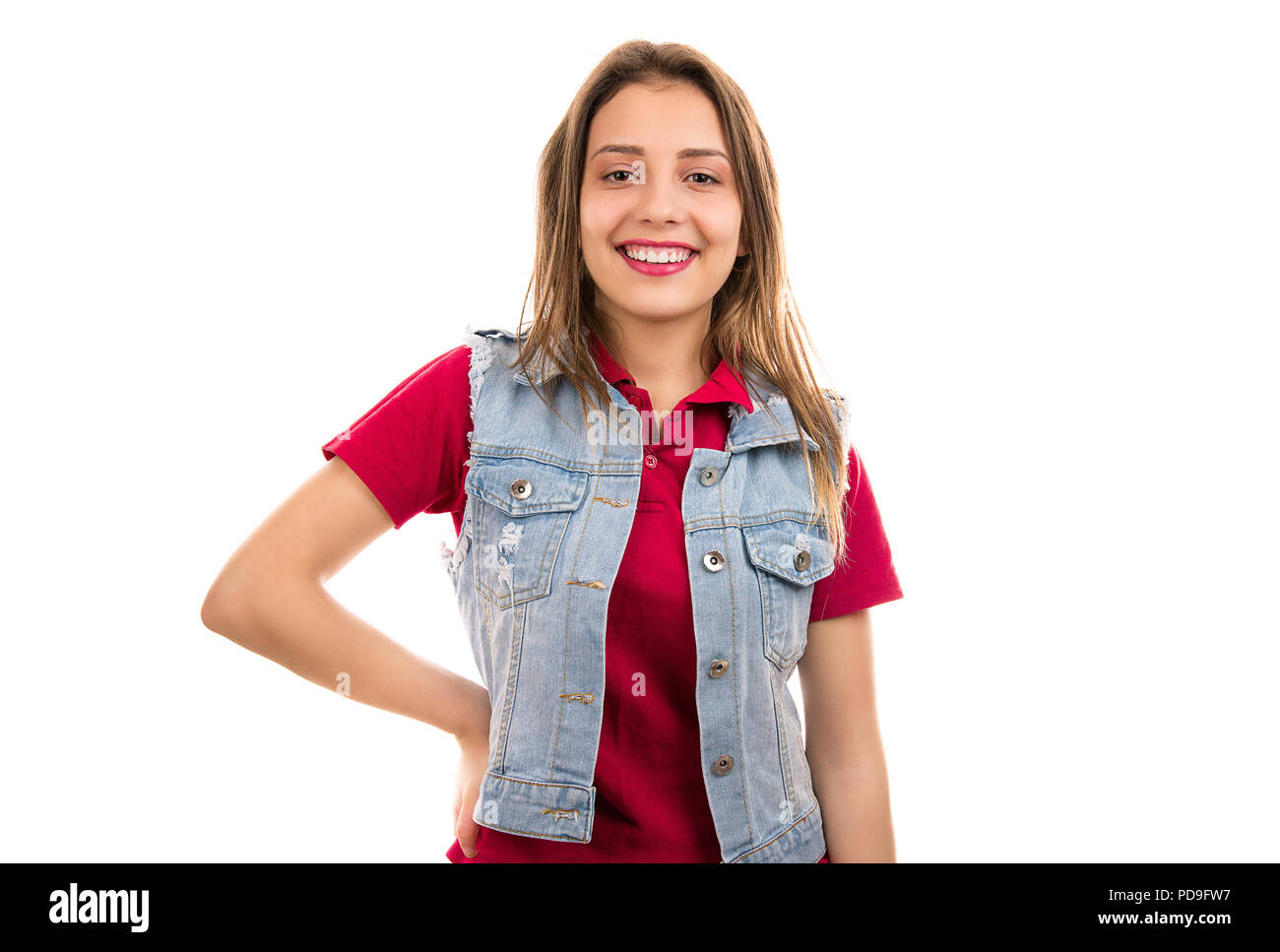 Piuttosto giovane donna in denim camicia in piedi con la mano sulla cintura e sorridente in telecamera isolata su sfondo bianco Foto Stock