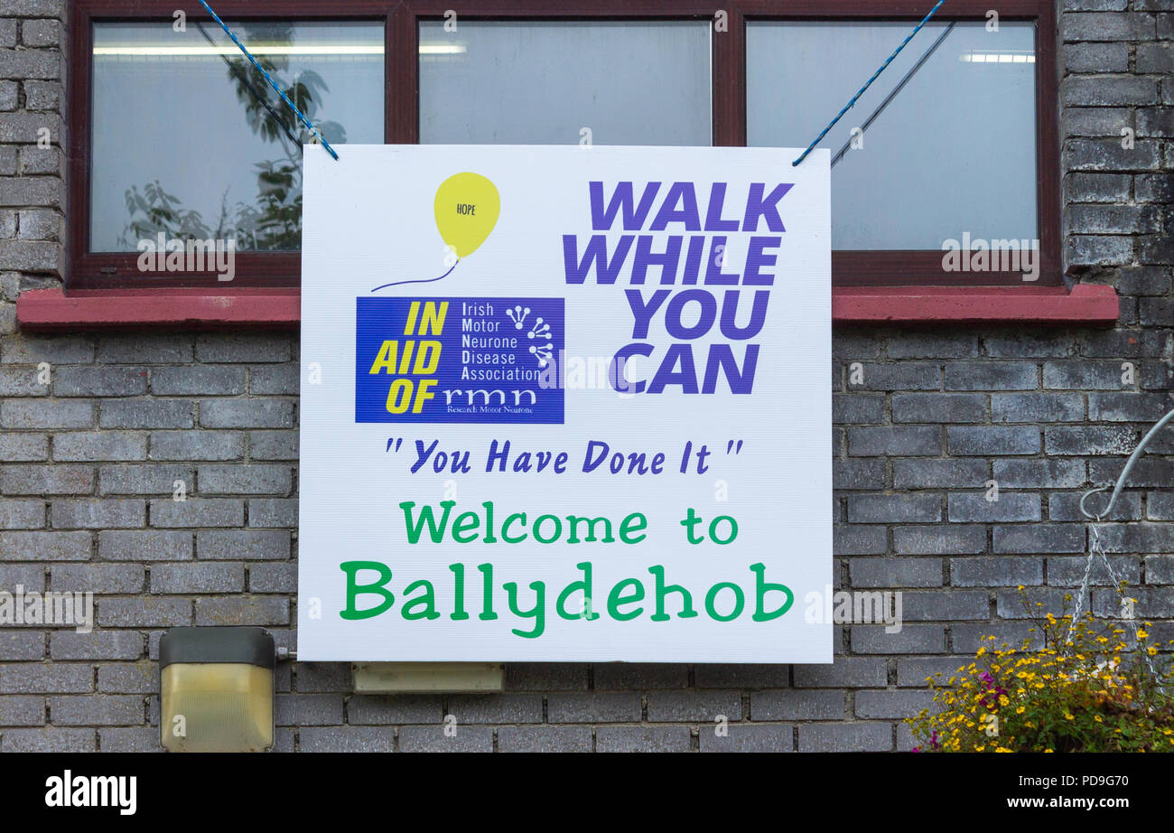 A piedi mentre è possibile banner per IMNDA Irish del motoneurone associazione malattia appesi da un edificio finestra. Foto Stock