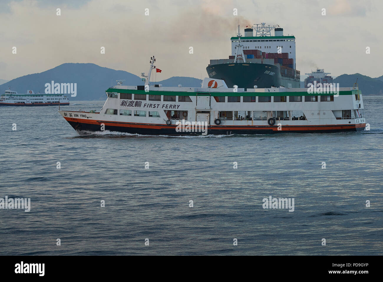 Un traghetto locale attraversa la prua della Evergreen nave portacontainer, mai il dolce, nella trafficata East Lamma canale di spedizione, Hong Kong. Foto Stock