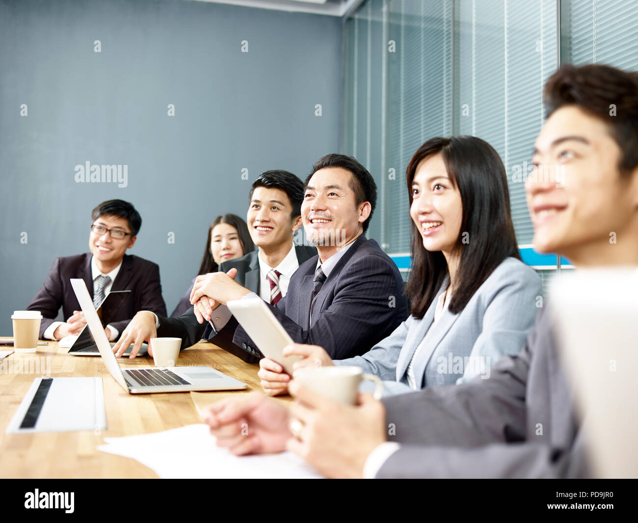Gruppo di sorridenti asian business aziendale persone che ascoltano la presentazione in office sala riunioni Foto Stock