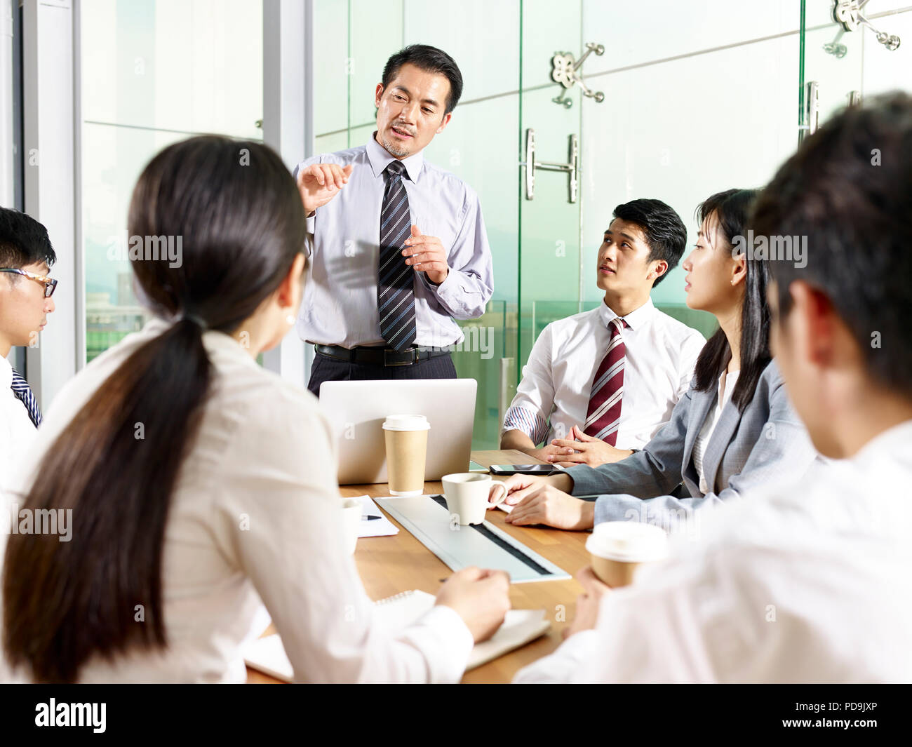 Asian business manager a parlare con il team durante la riunione in ufficio moderno. Foto Stock