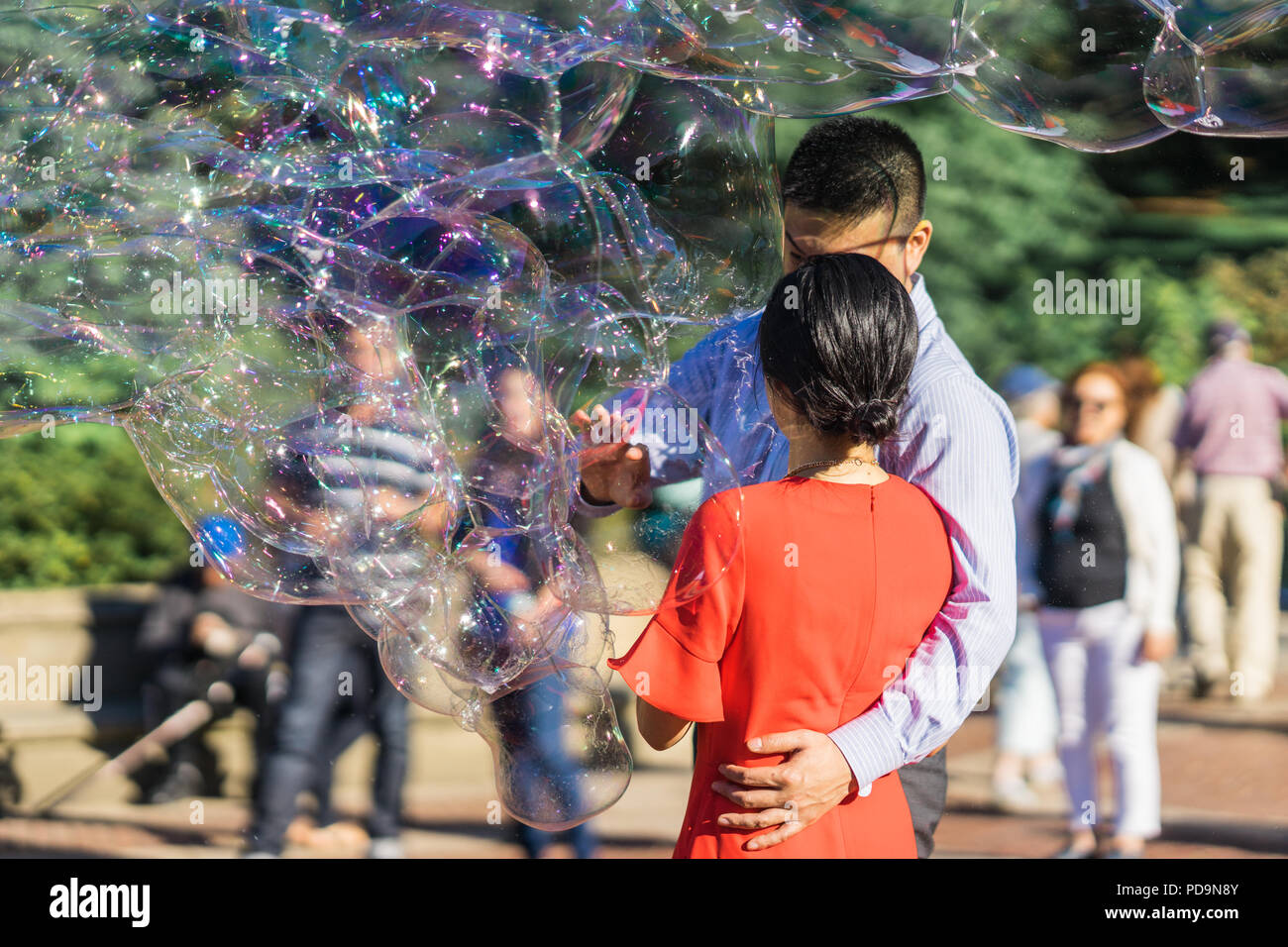 Giovane a giocare con il gigante arcobaleno bolle di sapone galleggianti in estate aria durante una bella giornata di sole. Divertente gioco divertente per i bambini e gli adulti. Foto Stock