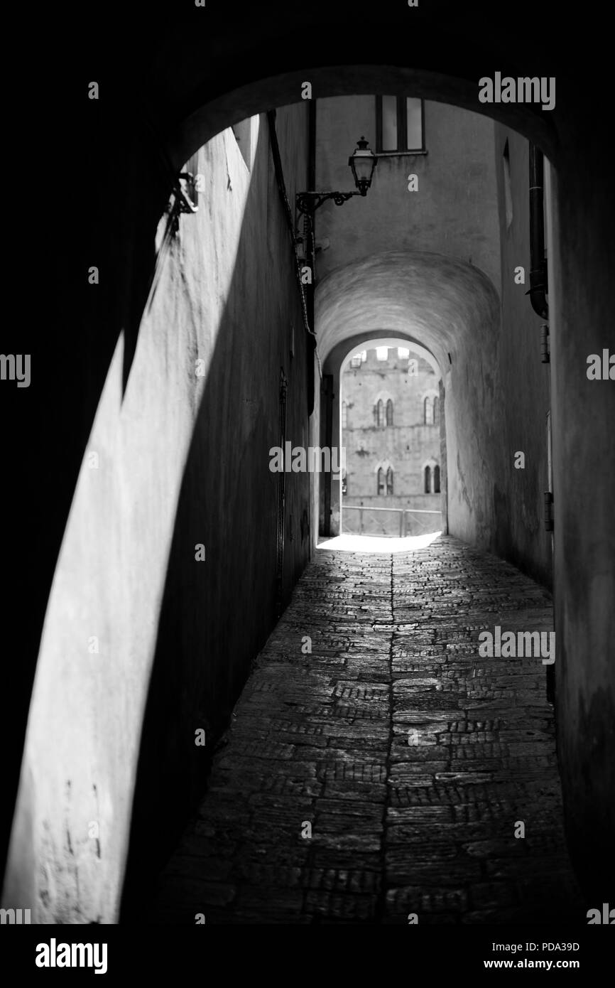 Un vecchio corridoio con un logorato piano con una vista attraverso la piazza principale di Volterra. In bianco e nero. Foto Stock