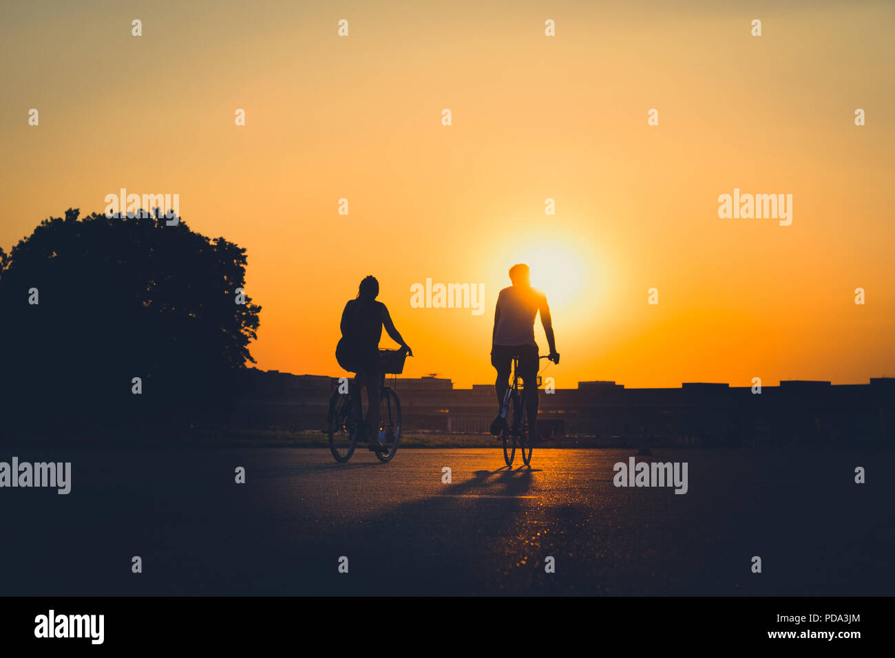 Silhouette di una persona in Bicicletta Equitazione con il tramonto sullo sfondo del cielo Foto Stock