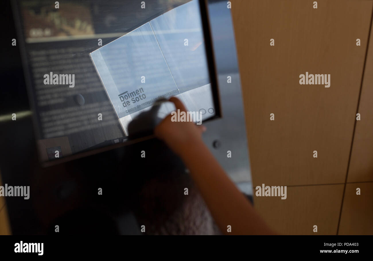 Trigueros, Spagna - Luglio 2nd, 2018: giovane visitatore utilizzando l'istruzione interattivi touch screen al centro visitatori del Dolmen de Soto, Huelva, Spagna Foto Stock