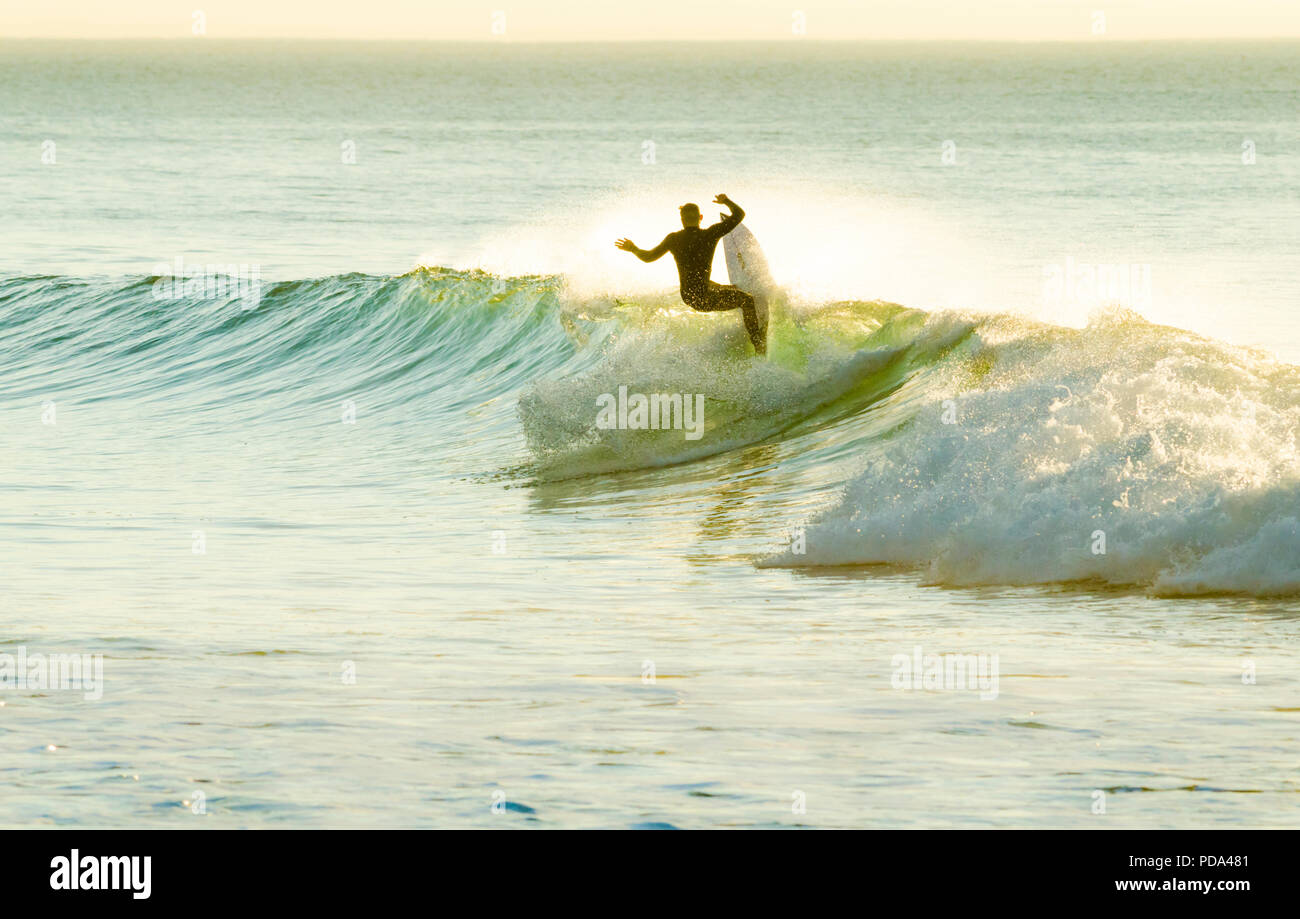 Surfer eseguendo un re-entry su un piccolo lato destro wave Foto Stock