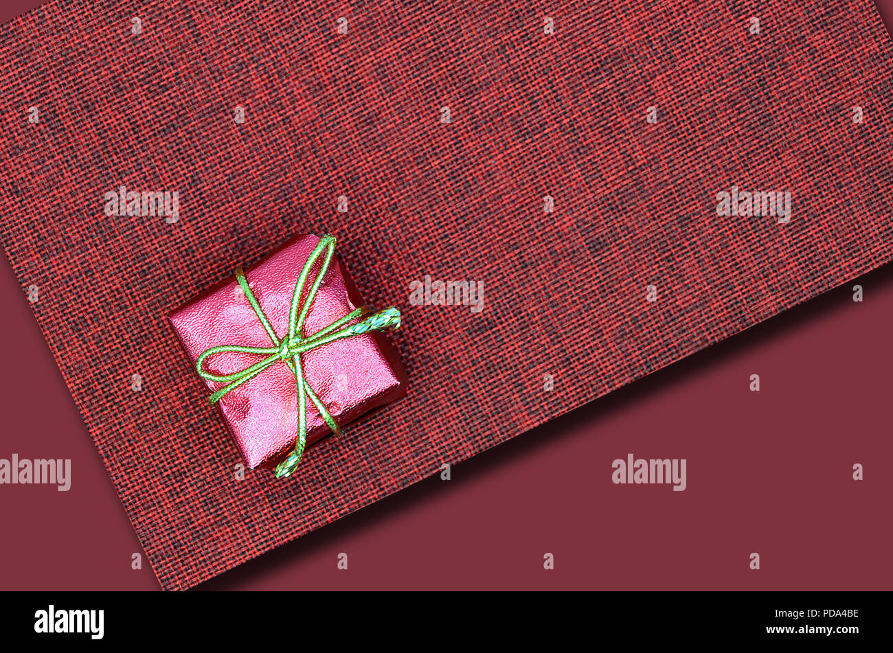 In prossimità di un piccolo pacco rosa sulla tela rossa, laici piatta Foto Stock