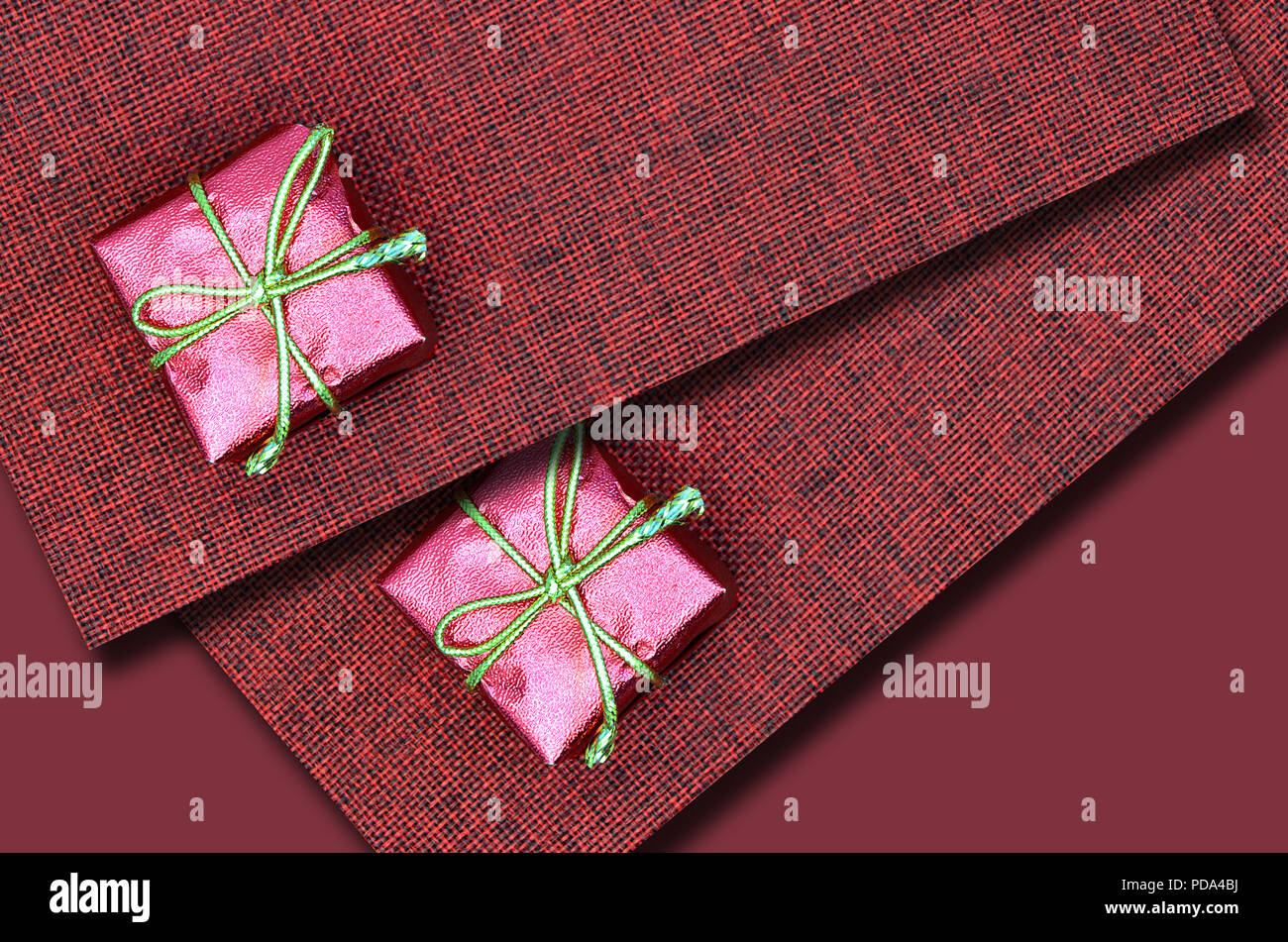 In prossimità di due piccoli pacchi rosa sulla tela rossa, laici piatta Foto Stock