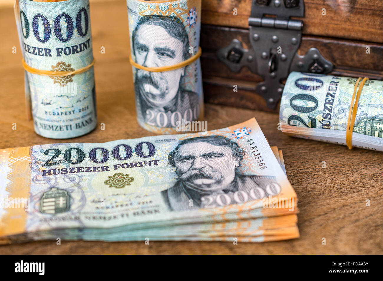 Pila di denaro ungherese (fiorini) e arrotolata 20000 banconote in fiorini ungheresi con un annata di chiusura scatola di legno in background Foto Stock
