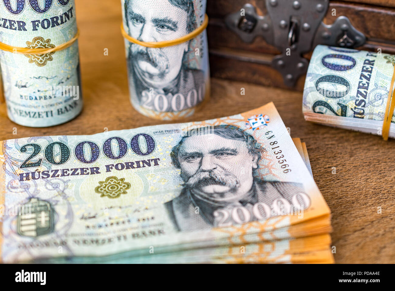 Pila di denaro ungherese (fiorini) e arrotolata 20000 banconote in fiorini ungheresi con un annata di chiusura scatola di legno in background Foto Stock