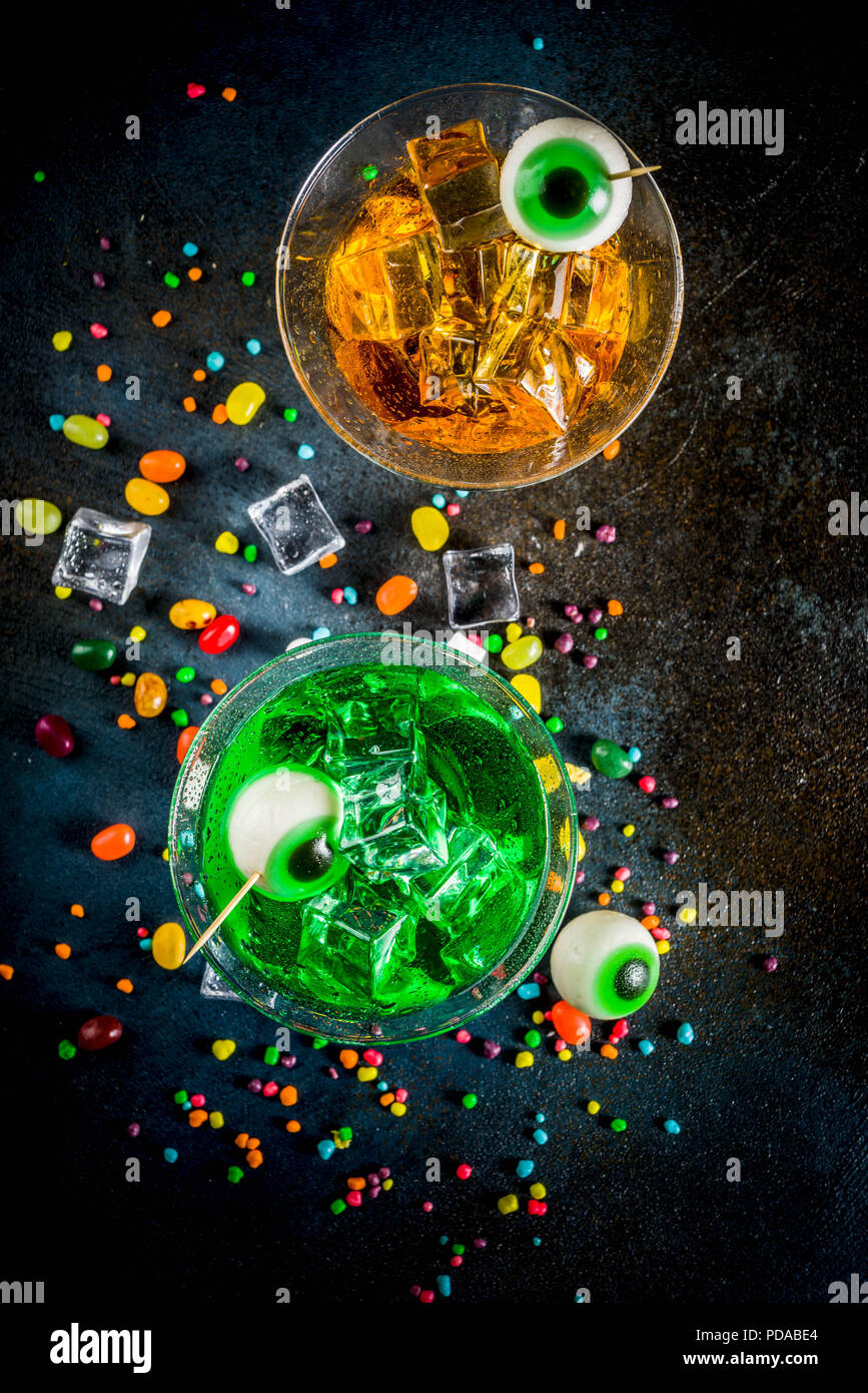 Spooky tratta per la festa di Halloween, un colore verde brillante, orange martini cocktail con cubetti di ghiaccio e un decor di marshmallow gli occhi. Su uno sfondo blu scuro, spazio Foto Stock