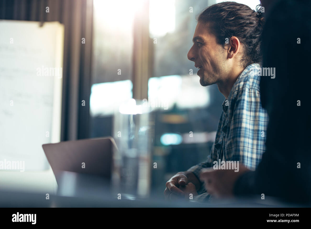 Felice giovane casuals seduta nella riunione di affari in ufficio. L'uomo durante un incontro strategico con i colleghi in sala riunioni. Foto Stock