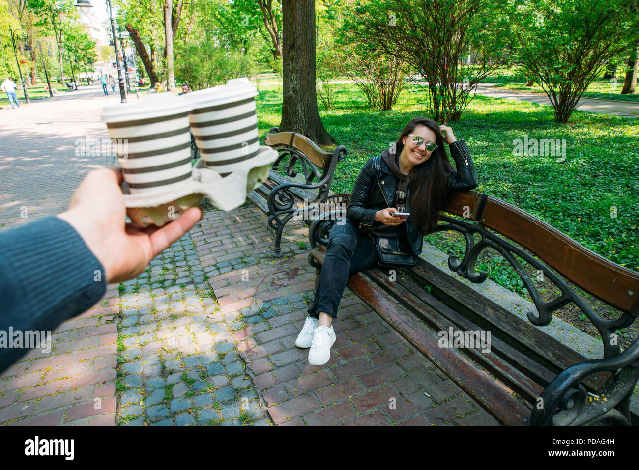 L'uomo portare il caffè per la giovane donna. data nel parco della città. Foto Stock