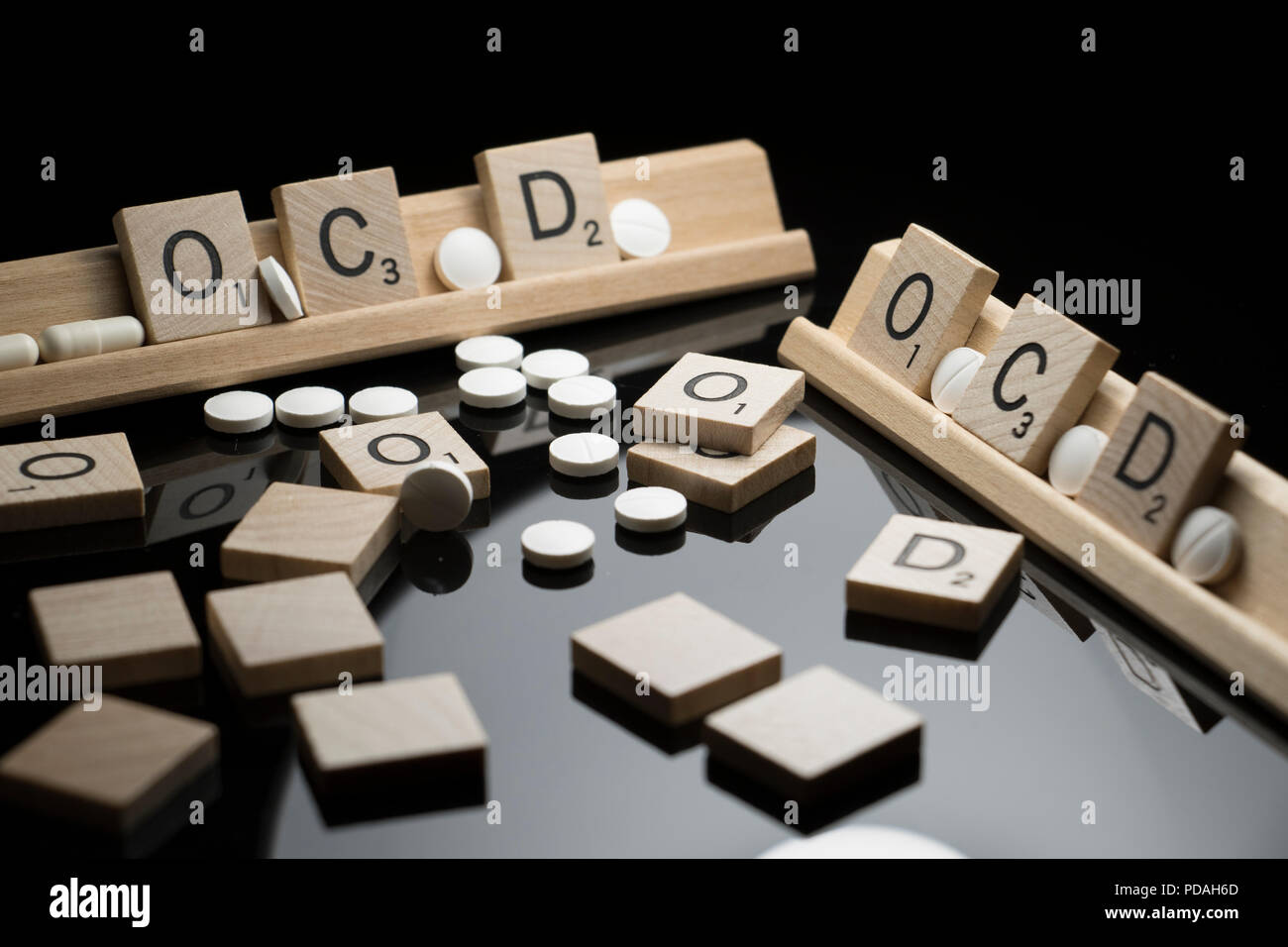 Concetto di OCD scritto nel testo di Scrabble con farmaci farmaceutici su una tavola nera. Disturbo ossessivo compulsivo e comportamento Foto Stock