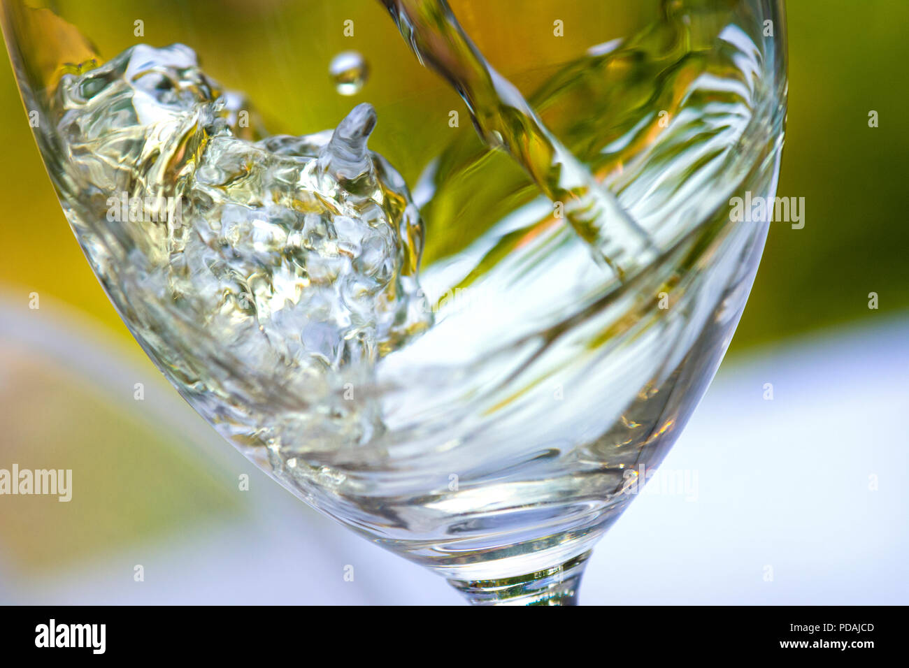 Versando un bicchiere di vino bianco close up azione cattura splash moto vorticoso nel fresco giardino estivo tabella situazione Foto Stock