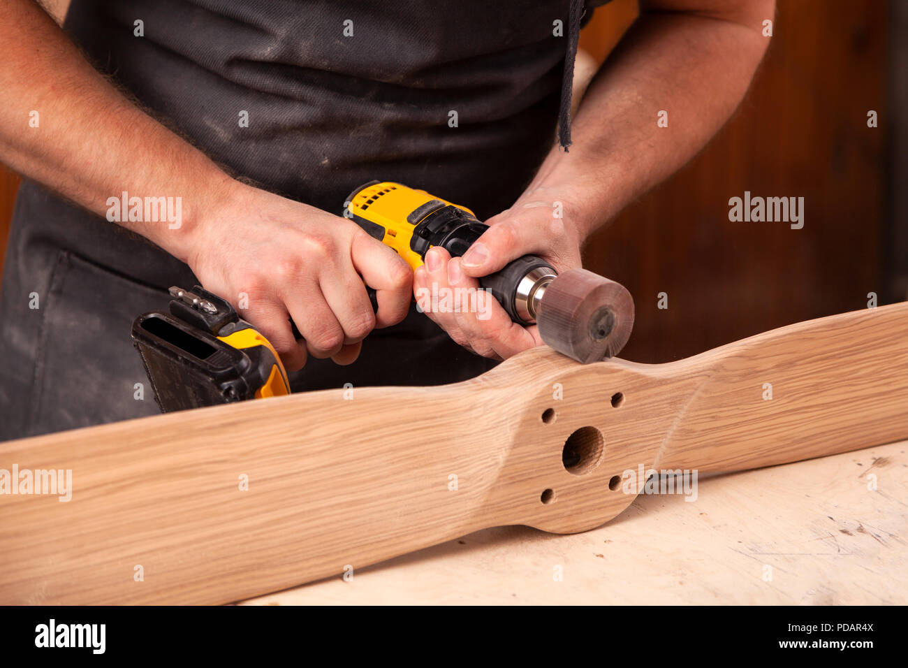 Close up di un giovane falegname builder è uguale a lucidi tavola di legno con una macchina lucidatrice o la levigatrice rotoorbitale in officina Foto Stock