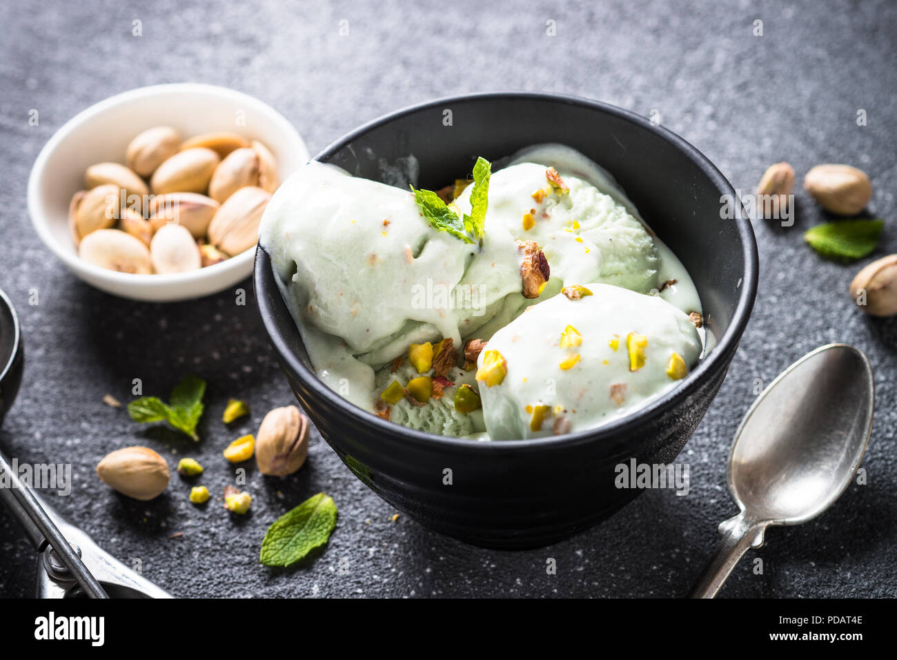 Pistacchi gelato in vaschetta nero sul tavolo di pietra. Foto Stock