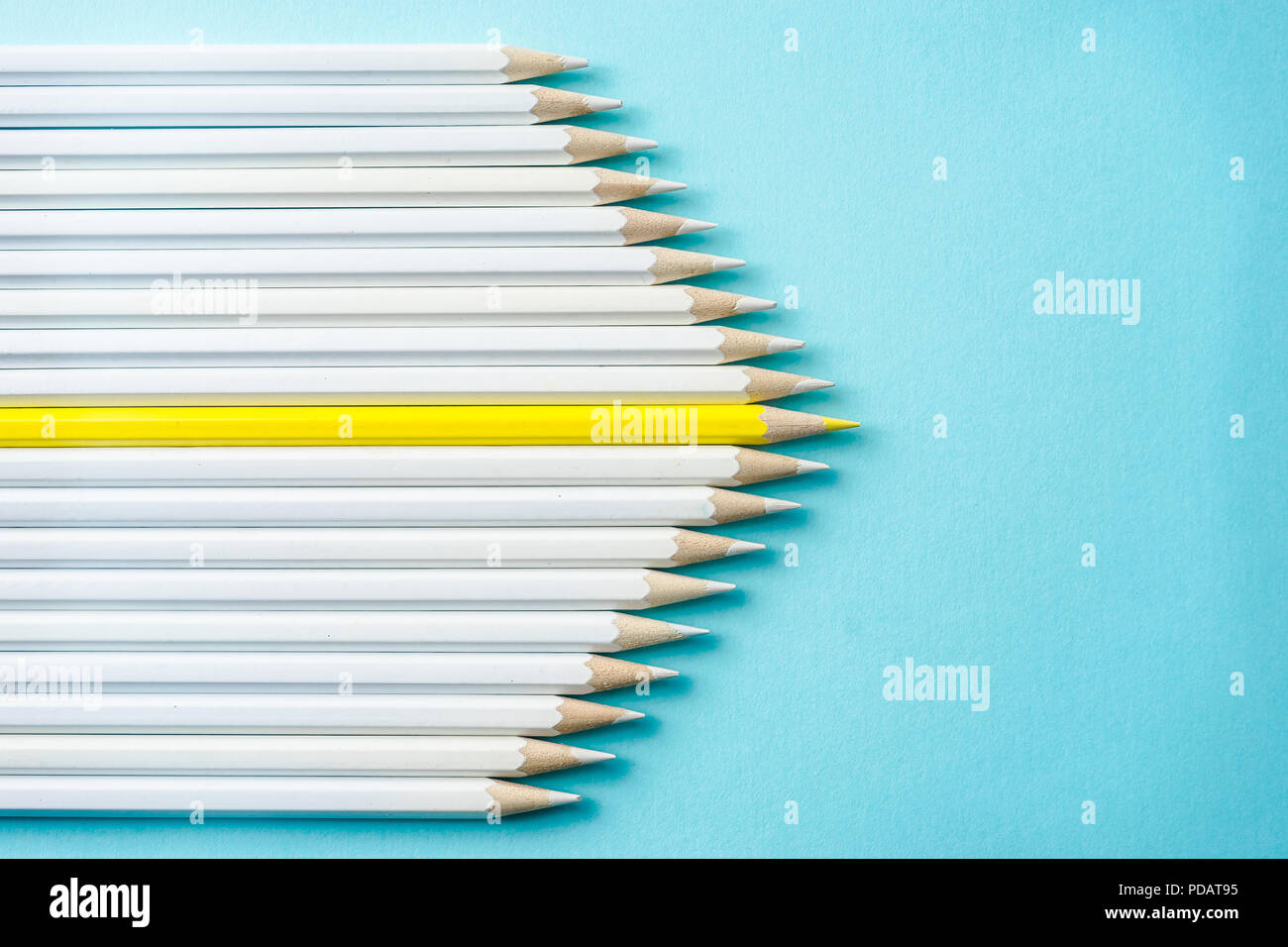 Il concetto di business - lotto di matite di colore bianco e una matita colorata su carta blu sullo sfondo. È il simbolo della leadership, il lavoro di squadra, uniti e comunicazione. Foto Stock