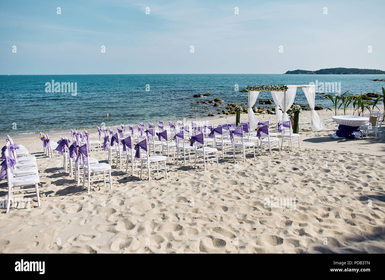 Spiaggia matrimoni impostazioni sulla sabbia bianca di mare bianco con sedie di Chiavari decorare con viola organza anta, minima decorazione floreale, p Foto Stock