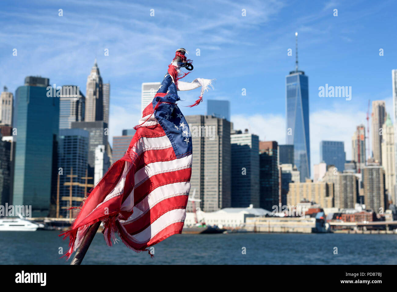 29-10-15, New York, Stati Uniti d'America. Un fuori fuoco Manhattan visto da Brooklyn, attraverso l'East River, con un consunto bandiera americana a fuoco in primo piano. Ph Foto Stock