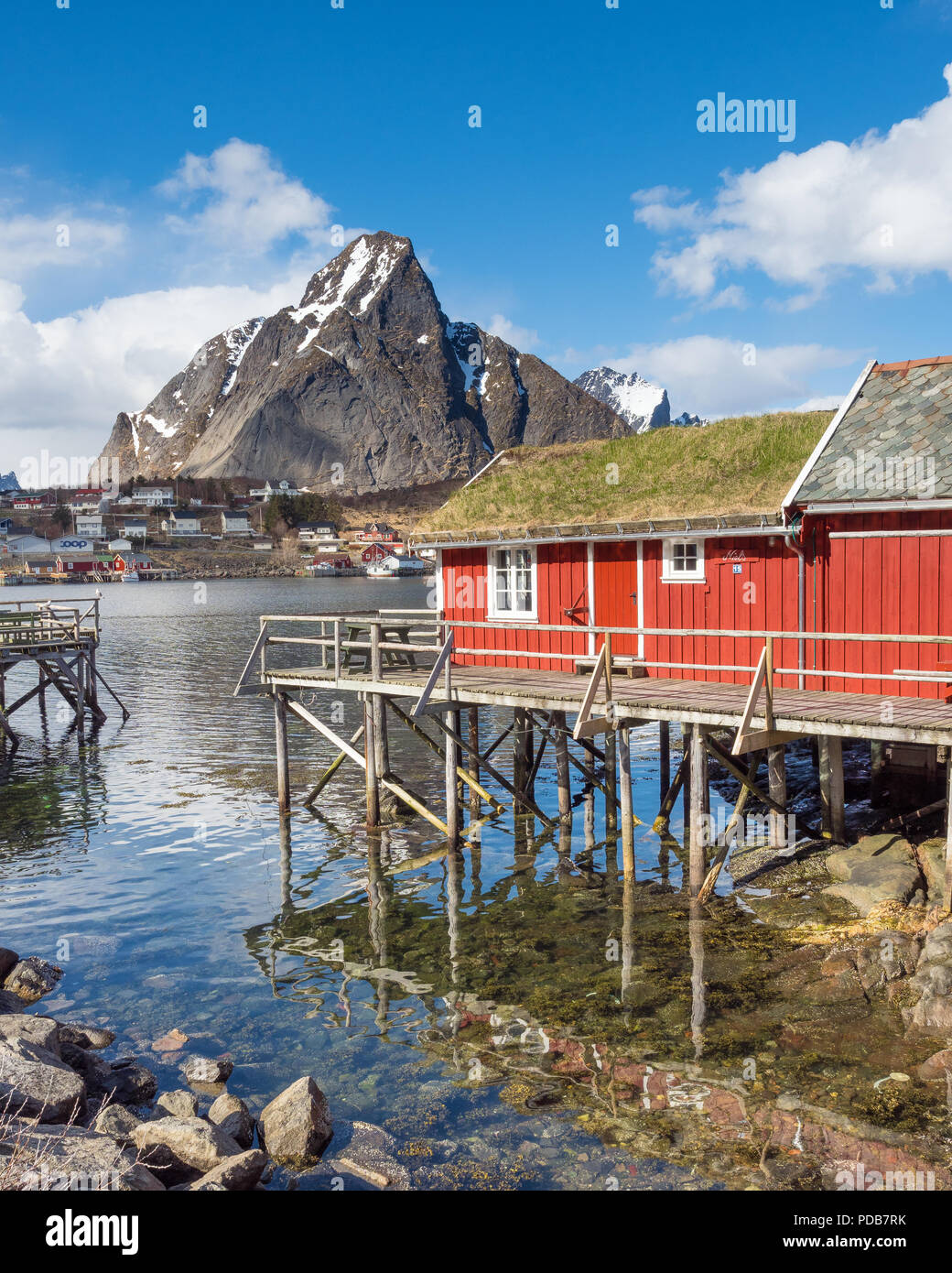 Un tradizionale rorbu (rosso pescatori cabina) è visto qui nel villaggio di Reine, Lofoten. Montare Olstind è in background. Foto Stock