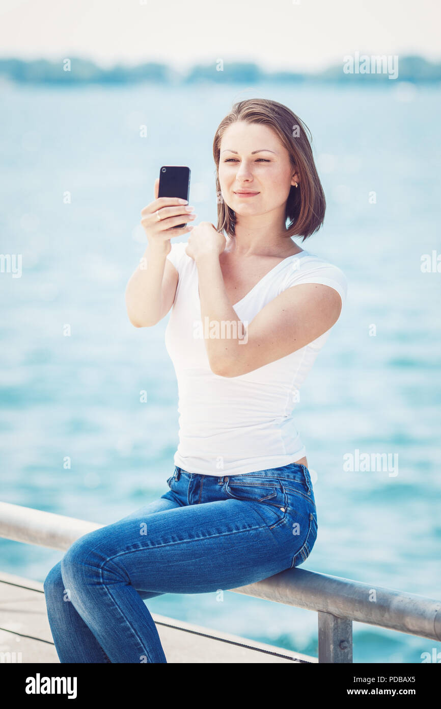 Ritratto di giovane e bella donna caucasici in bianco tshirt e jeans blu  con breve lungo bob haircut fuori dall'acqua facendo selfie foto con il suo  c Foto stock - Alamy