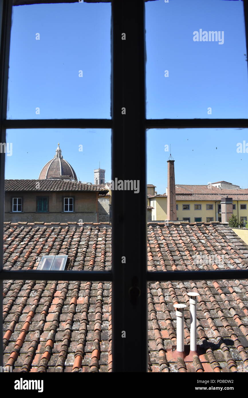 Una vista sui tetti di Firenze e il Duomo attraverso la finestra con il profilarsi sul telaio di una finestra che si affaccia sui tetti di terracotta Foto Stock