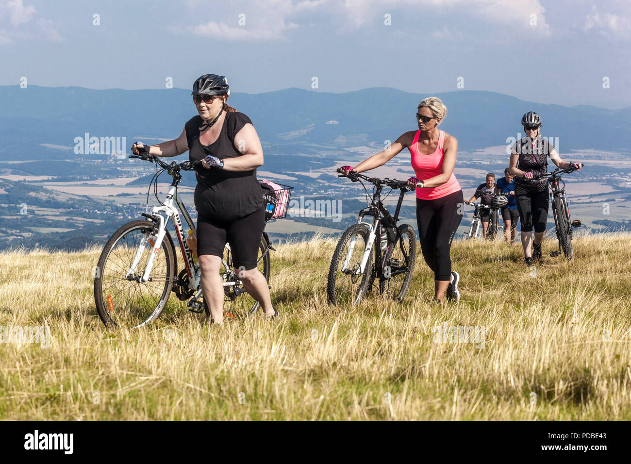 Donne in bicicletta, ciclisti in bicicletta su un sentiero di montagna, montagna Velka Javorina, confine ceco-slovacco nei Carpazi bianchi donne che spingono una salita Foto Stock