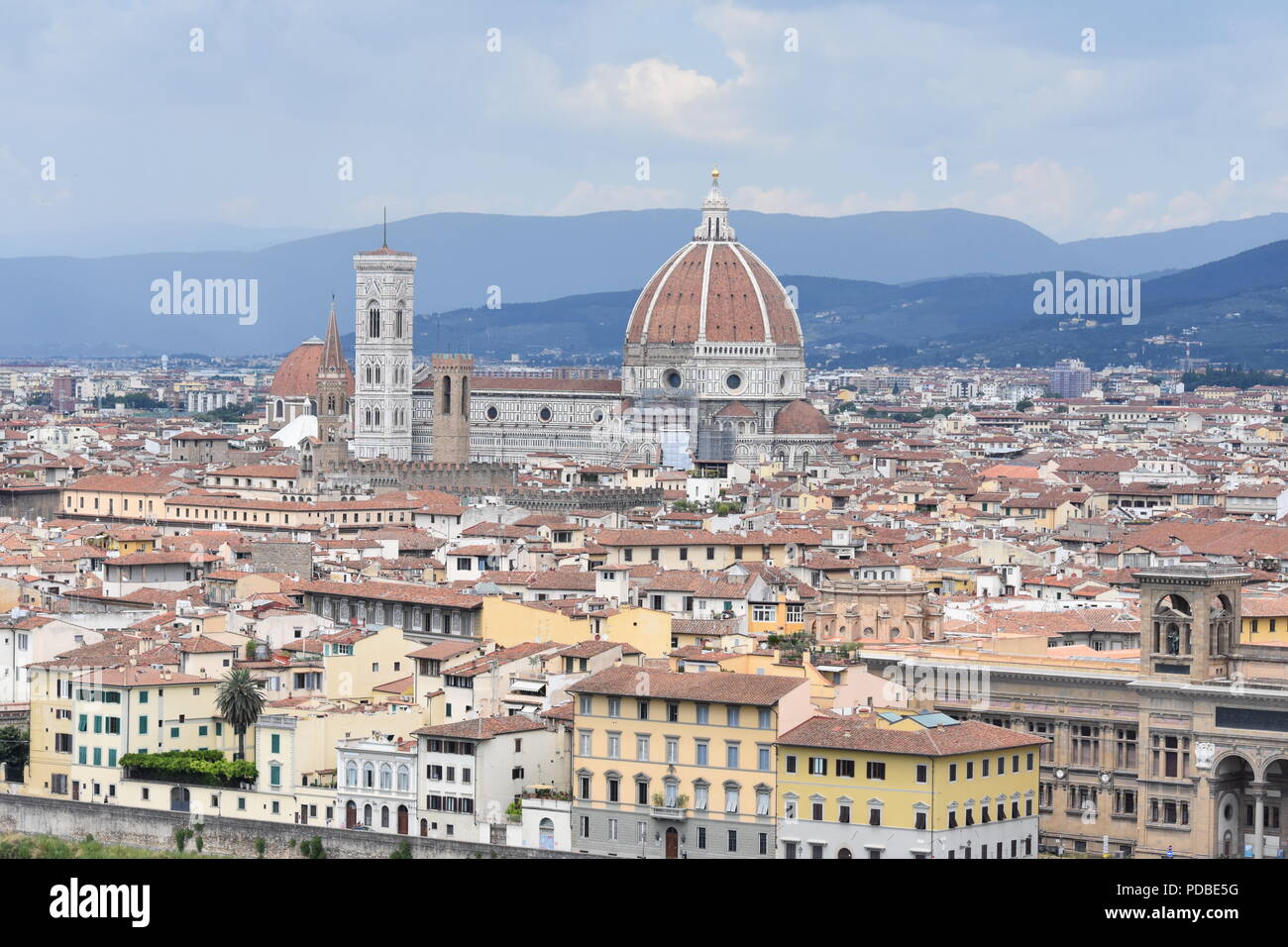 Riprese aeree del Duomo di Firenze e la torre tra i tetti di Firenze e sui tetti di terracotta. Sfondo di montagne nebuloso e grigio cielo molto nuvoloso Foto Stock